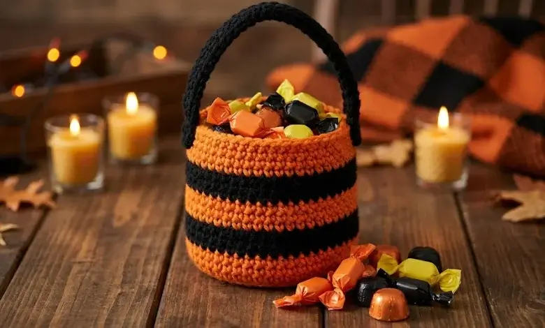 Orange and black striped crocheted trick-or-treat bag filled with wrapped candies on wooden surface