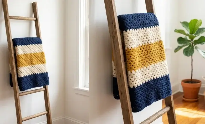 Continuous granny stitch stripe crochet blanket in navy cream and mustard yellow draped over a wooden ladder against a white wall