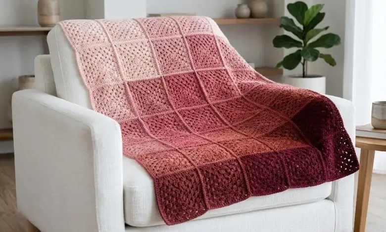 Free granny square crochet blanket with smooth ombre gradient from pale blush pink to deep burgundy draped over a white armchair