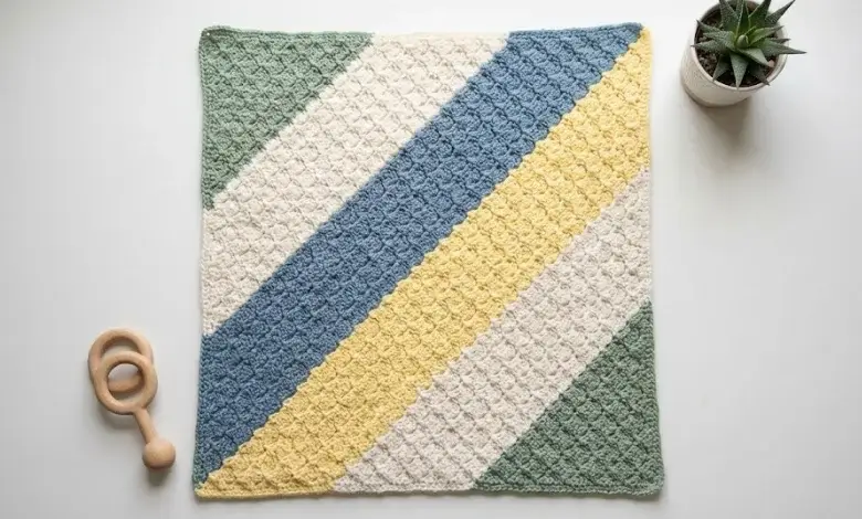Square baby crochet blanket in corner-to-corner C2C technique with diagonal color blocks in sage green cream and dusty blue