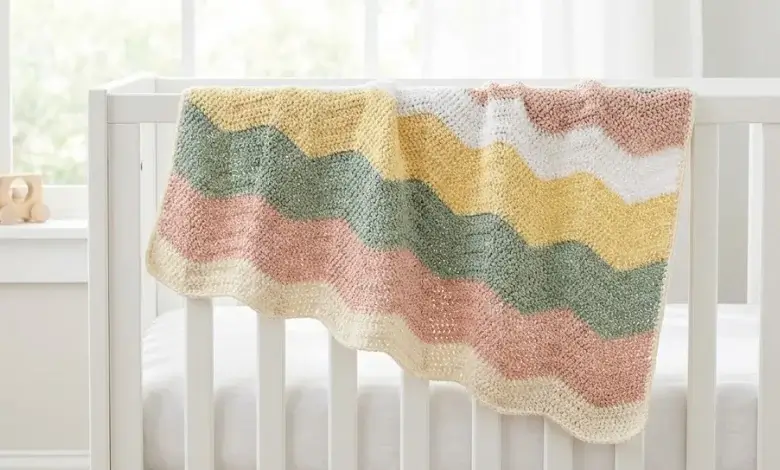 Soft baby crochet blanket with gentle shallow ripple wave pattern in five pastel colors draped over a white wooden crib