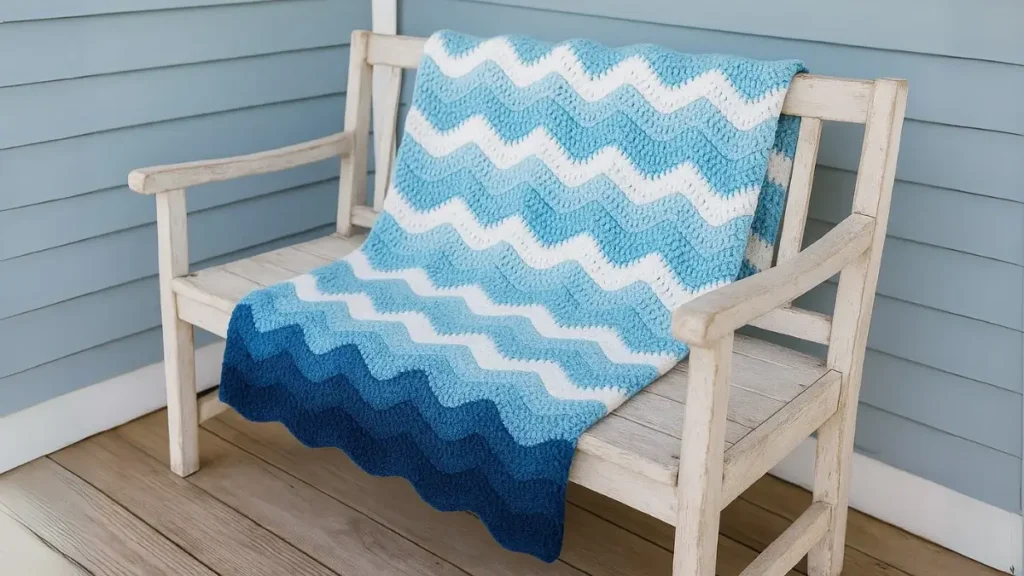 Blue and white cotton ripple throw displayed on a wooden porch bench in a summer setting.