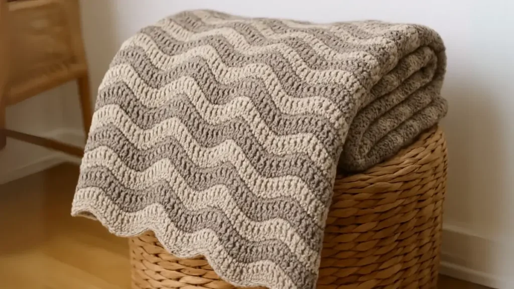 Neutral ripple crochet throw folded in a woven basket beside a sofa, beginner-friendly look.