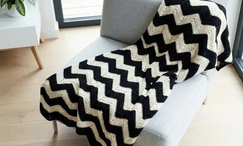 Black and cream crochet chevron throw blanket draped over a gray minimalist armchair
