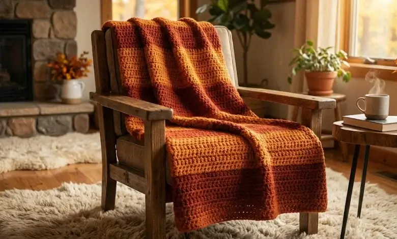 Burnt orange and rust crochet striped throw blanket draped over a wooden armchair by a fireplace