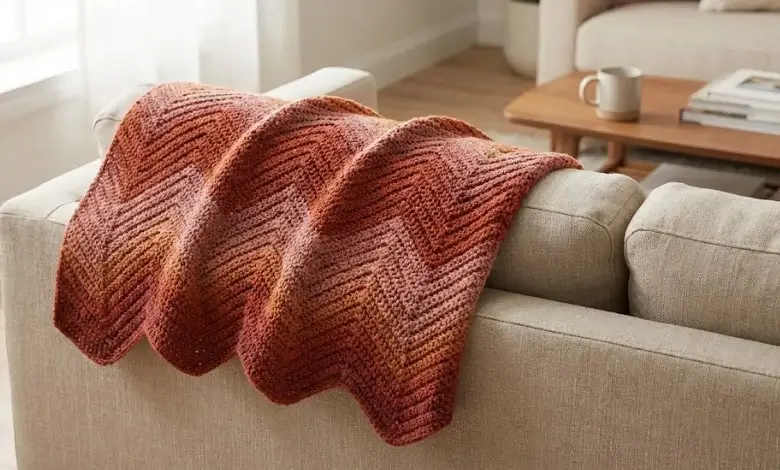 Terracotta and burnt orange crochet chevron throw blanket draped over a beige sofa